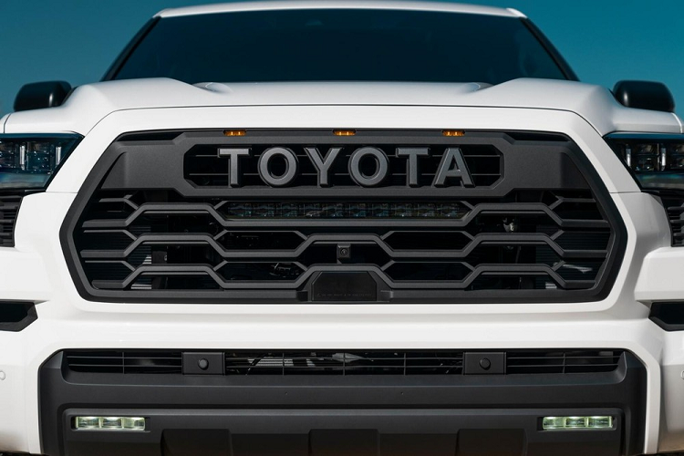 Trong khi đó, nội thất của xe dùng đen làm màu sắc chủ đạo. Nổi bật giữa nền đen là những chi tiết màu đỏ trên vô lăng, cần số và nút bấm khởi động máy. Chỉ khâu ở mặt cửa và bệ tì tay trung tâm của xe cũng màu đỏ. Ghế của Toyota Sequoia TRD Pro 2022 lại được bọc màu rằn-ri hầm hố, đậm chất nhà binh hơn. Trên mặt táp-lô còn có dòng chữ "Toyota" khá lớn màu đen.