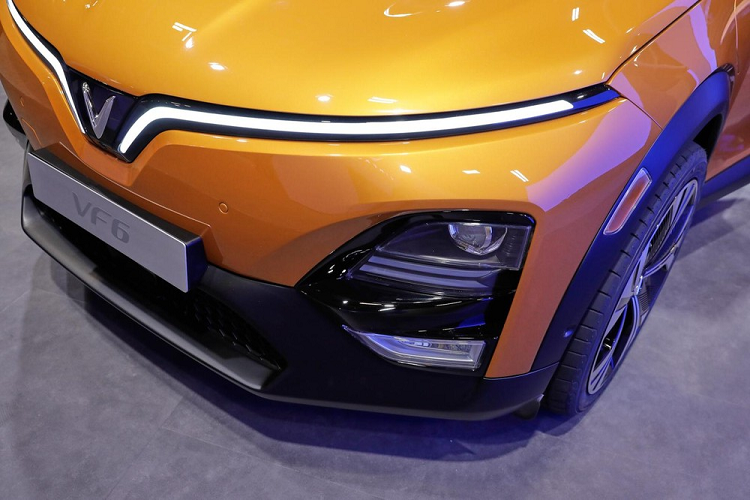 Tương tự nội thất, ngoại thất của VinFast VF6 cũng được thiết kế theo phong cách tối giản. Trên đầu xe, mẫu SUV điện này được trang bị dải đèn LED định vị ban ngày hình chữ "V", ôm lấy nắp ca-pô và kéo dài xuống logo của hãng. Trong khi đó, cụm đèn pha chính được đặt phía dưới, ở hai góc đầu xe. Bên trong cụm đèn này có đủ đèn chiếu xa, chiếu gần và đèn sương mù trước.