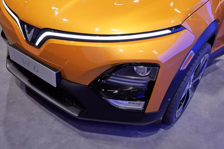 Tương tự nội thất, ngoại thất của VinFast VF6 cũng được thiết kế theo phong cách tối giản. Trên đầu xe, mẫu SUV điện này được trang bị dải đèn LED định vị ban ngày hình chữ "V", ôm lấy nắp ca-pô và kéo dài xuống logo của hãng. Trong khi đó, cụm đèn pha chính được đặt phía dưới, ở hai góc đầu xe. Bên trong cụm đèn này có đủ đèn chiếu xa, chiếu gần và đèn sương mù trước.