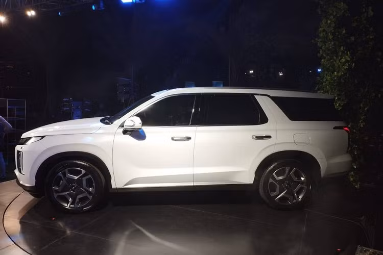 Ngoài ra, dải đèn LED này còn kéo dài xuống bên dưới, ăn sâu vào bên trong cụm đèn pha. Thiết kế này đẩy cụm đèn pha vào bên trong, sát với lưới tản nhiệt hơn trước. Trái với đầu xe, thiết kế bên sườn của Hyundai Palisade 2023 gần như không thay đổi, trừ bộ vành la-zăng. Trong khi đó, ở khu vực đuôi xe, mẫu SUV cỡ lớn này được bổ sung cản sau mới, tích hợp tấm ốp gầm dày hơn và đầu ống xả giả vuông vức.