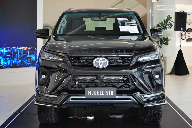 Nhờ gói phụ kiện Modellista - đối tác ruột của hãng Toyota, mẫu SUV hạng D này có thêm ốp cản trước và ốp cản sau mới. Thêm vào đó là tem chữ nổi "Modellista" được sơn màu đen bóng nằm trên nắp ca-pô và nẹp mạ crôm hình chữ "Y" mới ở hai góc cản trước.