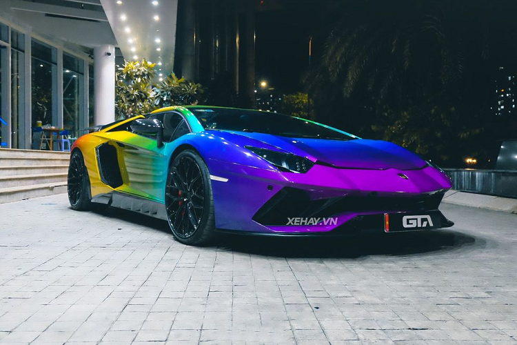 Phần cản trước của chiếc Lamborghini Aventador Roadster hàng hiếm này đã được nâng cấp lên bản Aventador S, tiếp đến là màu sơn ngoại thất 7 sắc cầu vồng vô cùng nổi bật. Tính đến thời điểm hiện tại, thì đây là chiếc Lamborghini Aventador thứ 2 tại Việt Nam mang màu sơn ngoại thất sặc sỡ này.