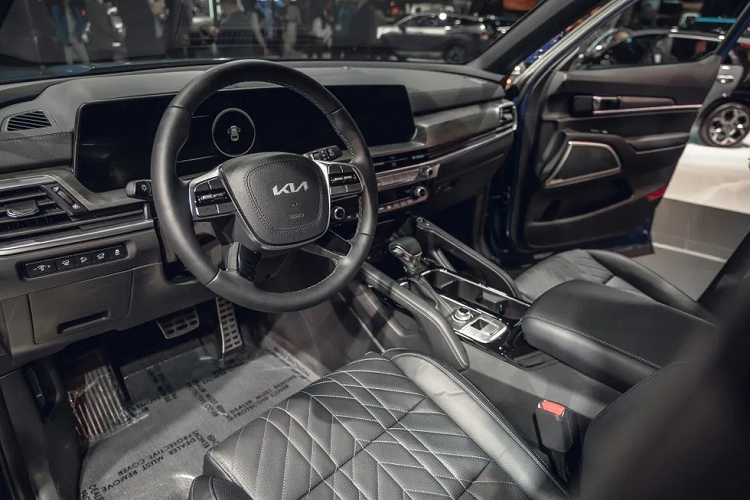 Bước vào bên trong Kia Telluride 2023, người lái sẽ bắt gặp những trang bị mới như bảng đồng hồ kỹ thuật số và màn hình thông tin giải trí nối liền với nhau, cả hai đều có kích thước 12,3 inch. Vì sự xuất hiện của màn hình cong này mà mặt táp-lô và vô lăng của xe cũng phải thay đổi thiết kế cho phù hợp.