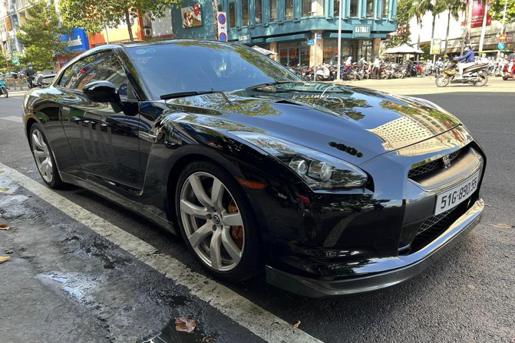 Điểm nhấn trên xe là dòng chữ UN nằm ở 2 bên cửa xe, một chi tiết đặc biệt trên tất cả các mẫu xe mà ông Vũ sở hữu. Bộ mâm xe là loại đa chấu được sơn xám, đi kèm cùm phanh màu cam. Có thể thấy, cặp ống xả của chiếc Nissan GT-R R35 của Qua Vũ đã được thay loại ống xả độ bằng chất liệu Titanium.