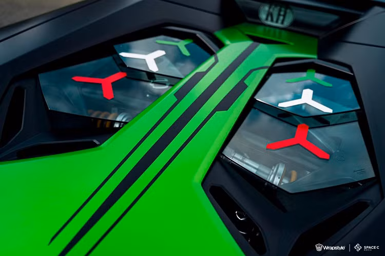 Bộ áo này vẫn lấy tông màu xanh lá làm chủ đạo nhưng có thêm màu đen tạo điểm nhấn và các viền trắng như thể hiện một đường đua, nơi mà siêu phẩm Lamborghini Essenza SCV12 có thể tung hoành hết sức mạnh 819 con ngựa của mình. Trên mỗi chiếc siêu xe đua Lamborghini Essenza SCV12 sẽ có con số 63 xuất hiện nhưng trên bộ áo của xe Lamborghini Aventador LP700-4 Roadster này lại thay bằng 68, nhiều khả năng ám chỉ quê hương của chủ xe.