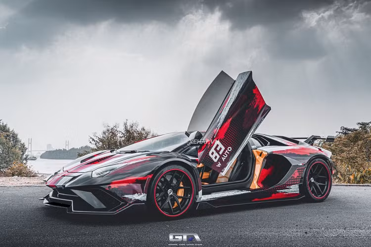 Chiếc Lamborghini Aventador trong bài được hoàn thiện với bộ tem mang tông màu đỏ - đen – trắng được thực hiện bởi đội ngũ GTA Wrapping. Với “bộ áo” mới này, Lamborghini Aventador chắc chắn sẽ rất nổi bật khi lăn bánh trên đường phố Việt.