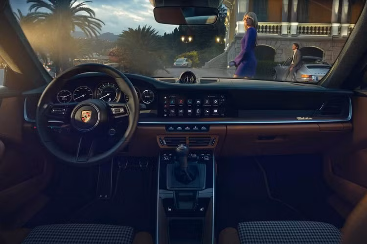 Mở cửa bước vào trong khoang lái, đập vào mắt chủ nhân của xe Porsche 911 Sport Classic 2023 là dòng chữ 911 Sport Classic trên bậc cửa như khẳng định đây là xe giới hạn Porsche 911 Sport Classic 2023, ngoài ra, ghế ngồi xe bọc da Cognac cổ điển sáng màu tương phản với họa tiết caro, các họa tiết Houndstooth cũng xuất hiện trong nội thất xe Porsche 911 Sport Classic 2023 của Cường Đô la đặt mua.