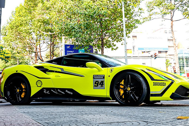 Đặc biệt, phần đèn pha còn được dán decal một phần để mang đến cái nhìn sắc sảo và táo bạo hơn. Nhiều vị trí trên xe xuất hiện số 94. Nhìn tổng thể, Ferrari 488 GTB vô cùng ấn tượng nhờ màu sơn “phát sáng” cùng bộ tem đua bắt mắt.