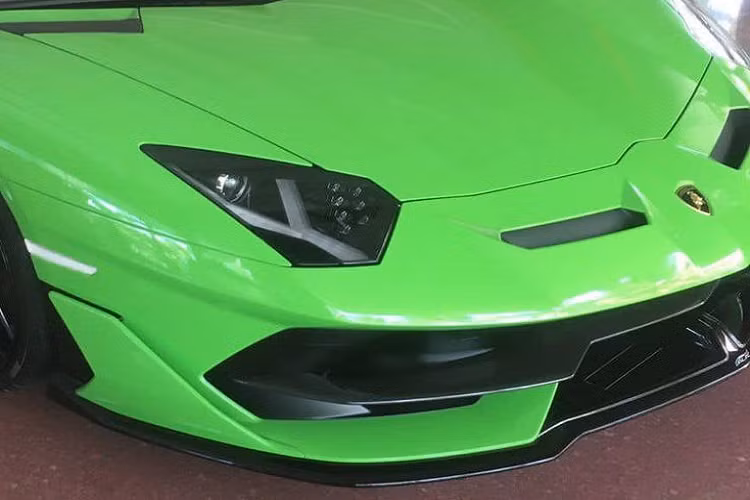 Lamborghini Aventador SVJ Roadster gây ấn tượng với phần đầu xe thiết kế mạnh mẽ với nhiều đường cắt xẻ táo bạo cùng loạt vây, khe gió để tăng hiệu quả động lực học. Khi nhìn từ đầu xe, nổi bật là cụm đèn pha góc cạnh cùng với dải đèn LED bắt mắt với những chiếc bóng đèn nhỏ bên trong.