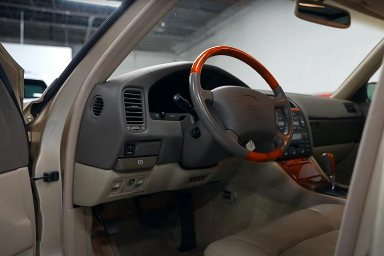 Trong khi đó, nội thất giữ được màu nguyên bản với những chi tiết bọc da không có dấu hiệu bị nhăn nhúm, nứt hay xuống cấp. Gỗ ốp trên vô lăng, cần số và cụm điều khiển trung tâm vô cùng bóng bẩy. Thảm trải sàn của chiếc Lexus LS400 cũng là trang bị nguyên bản, chưa từng được thay thế.