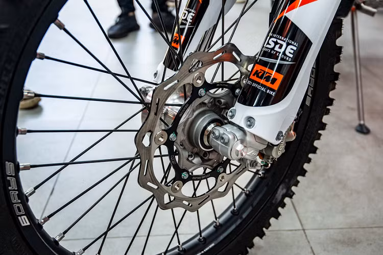 Hệ thống phanh trang bị trên KTM 350 EXC-F Six Days 2022 là thương hiệu Brembo với heo trước trước 2 piston và heo sau 1 piston. Phần yên được bọc da màu xanh dương phối với màu cam tạo điểm nhấn.