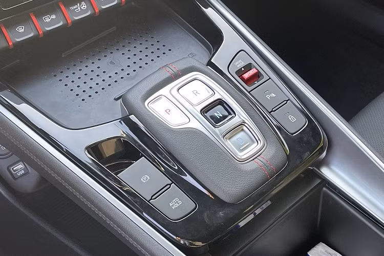 Bên dưới là sạc điện thoại thông minh không dây, các nút bấm chuyển số, phanh tay điện tử, tính năng tự động giữ phanh tạm thời và bộ bàn đạp bằng kim loại.