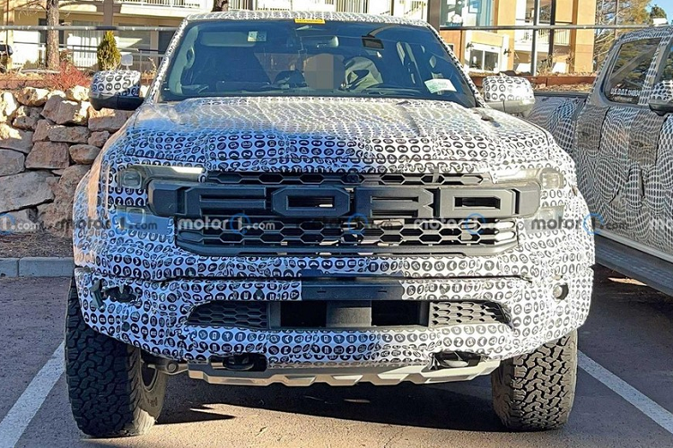 Chưa hết, màn hình thông tin giải trí của Ford Ranger Raptor 2022 còn được đặt giữa 2 cửa gió điều hòa trung tâm. 2 cửa gió này được thiết kế dọc và đi kèm viền màu đỏ thể thao. Bên ngoài, Ford Ranger Raptor 2022 được ngụy trang khá kỹ nhưng chúng ta vẫn có thể nhận ra một số chi tiết thiết kế của xe. Cụ thể, trên đầu xe xuất hiện dòng chữ "Ford" cỡ lớn ở giữa lưới tản nhiệt. Đây vốn là đặc điểm nhận dạng chung của các mẫu xe Raptor như Ford Ranger Raptor, Bronco Raptor và F-150 Raptor.