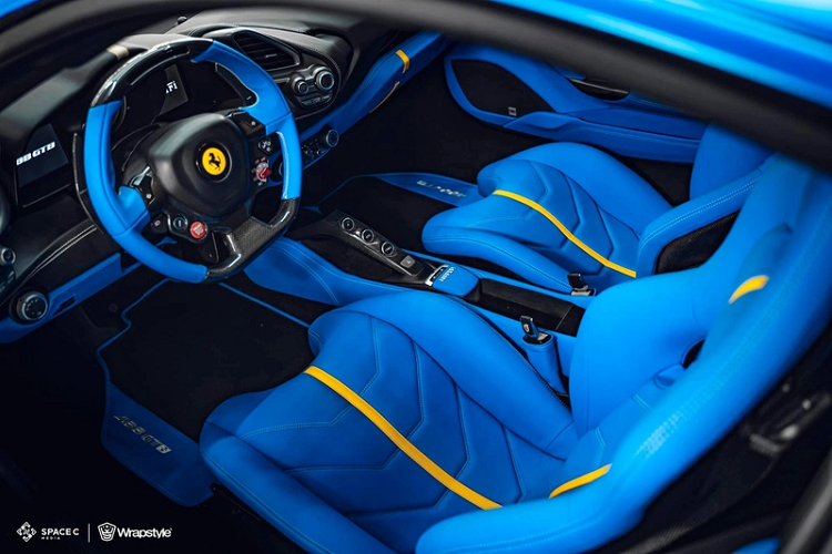 Không chỉ được thay đổi ở bên ngoài, chiếc 488 GTB của đại gia An Giang còn được bọc lại toàn bộ nội thất với da màu xanh dương Racing Blue, kết hợp chỉ khâu màu trắng và sọc vàng thay vì tông màu da bò như cũ. Cabin xe cũng có nhiều chi tiết sợi carbon như vô-lăng, cụm nút chuyển các chế độ lái, ốp phía sau ghế ngồi.