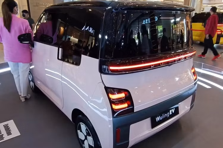 Bên dưới dải đèn LED định vị ban ngày là cổng sạc của xe với nắp tích hợp logo có thể phát sáng của thương hiệu Wuling. Tiếp đến là cụm đèn pha 2 bóng có kích thước khá lớn và được bao quanh bằng viền màu đen. Ngoài ra, xe còn có cản trước không sơn màu, tích hợp đèn sương mù và hốc gió trung tâm. Bên sườn, mẫu xe này chỉ có 2 cửa đồng thời được trang bị bộ vành có đường kính 12 inch, nằm trong lốp 145/70 R12 và đi kèm chụp la-zăng màu đen - trắng.