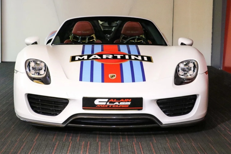 Việt Nam hiện chỉ có 2 chiếc siêu xe Porsche 918 Spyder, và không có chiếc nào giống với chiếc xuất hiện cạnh đại gia Hoàng Kim Khánh. Cụ thể, xe có ngoại thất màu trắng kèm tem Martini Racing độc đáo - chi tiết từng có trên nhiều dòng xe đua của Porsche.