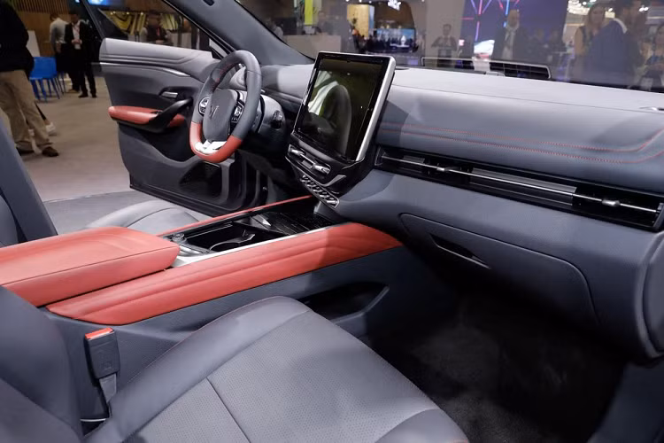 Qua những hình ảnh chụp tại triển lãm Ô tô Paris 2022, có thể thấy VinFast VF7 được trang bị nội thất có thiết kế thể thao hơn so với người anh em VF6. Có được điều đó là nhờ vô lăng vát đáy thể thao và bọc da phối 2 màu xám - đỏ tương phản, tương tự ghế trước/sau của xe.