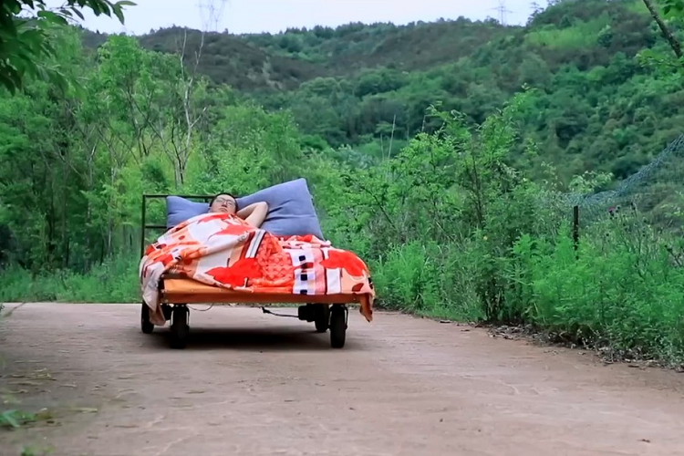 Phần đầu giường có thể nâng lên, hạ xuống theo ý thích. Ngoài ra, chiếc giường di động của người đàn ông này còn được tích hợp cả bạt che để trở thành lều tránh mưa, nắng. Khi không dùng đến, phần bạt che sẽ được cất gọn ở đuôi giường.