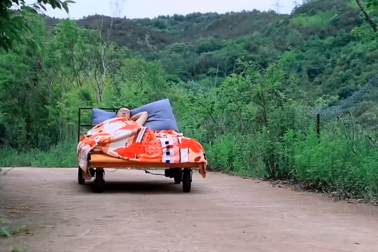 Phần đầu giường có thể nâng lên, hạ xuống theo ý thích. Ngoài ra, chiếc giường di động của người đàn ông này còn được tích hợp cả bạt che để trở thành lều tránh mưa, nắng. Khi không dùng đến, phần bạt che sẽ được cất gọn ở đuôi giường.