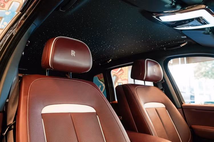 Mở cửa bước vào bên trong khoang lái, chiếc xe SUV siêu sang Rolls-Royce Cullinan Black Badge đang được chào bán hơn 39 tỷ đồng có nội thất bọc da màu đỏ và điểm ấn tượng là rất nhiều chi tiết của khoang lái ốp carbon bóng đắt tiền. Xe cũng có logo vô cực xuất hiện bậc cửa, đồng hồ của xe hay nằm trên cao, chính giữa của bệ tỳ tay hàng ghế sau.