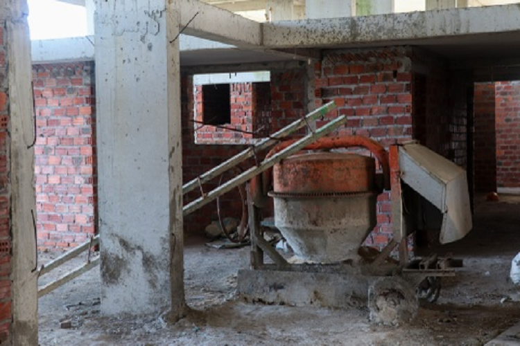 Máy trộn bê tông để trên tầng một khu chung chưa chưa hoàn thiện đang có dấu hiệu hoen gỉ. Một block chung cư trong dự án đổ sàn dang dở nhưng chủ đầu tư không tiếp tục thực hiện. Các khung sắt vẫn trơ trọi nằm phơi nắng, phơi mưa.