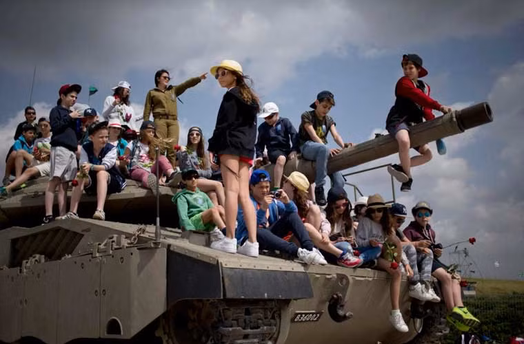 Các em học sinh tới từ Bỉ được ngồi lên cỗ tăng của Quân đội Israel trong chuyến thăm tới quốc gia này.