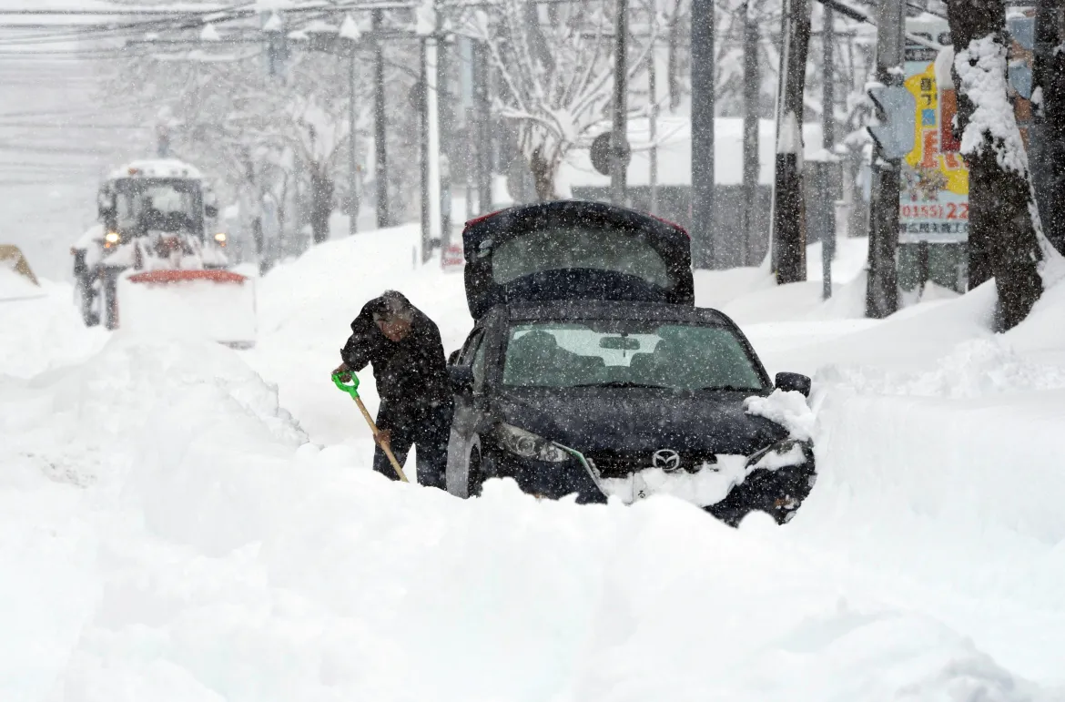 Những đoạn video được đăng tải cho thấy cảnh người dân dọn tuyết và hành khách đẩy những chiếc xe bị mắc kẹt. Ảnh: EPA.