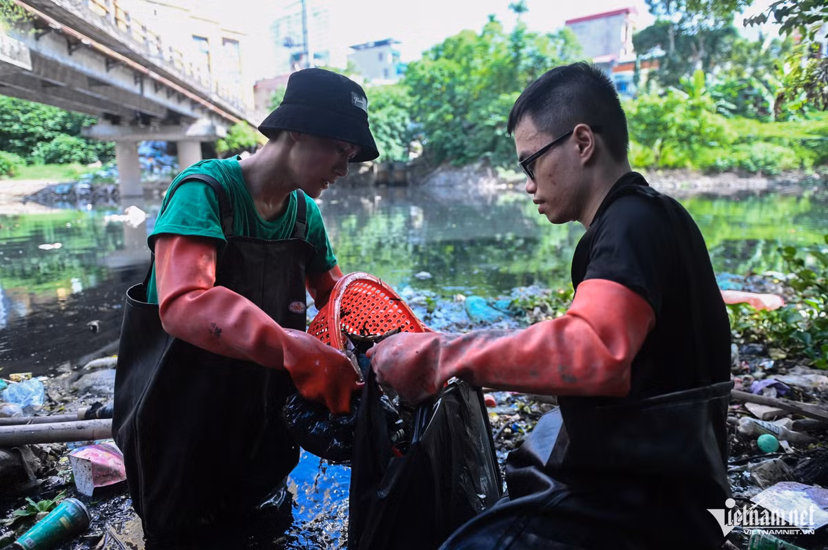 Sau khi đám rác trôi nổi được kéo vào gần, các chàng trai dùng rổ vớt lên cho vào túi nilon.