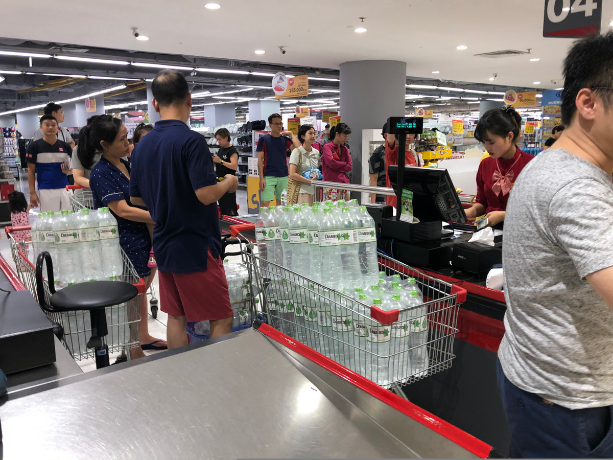 Khách hàng nối đuôi nhau chờ đến lượt thanh toán. Trên xe chất đầy hầu hết là nước khoáng đóng chai.