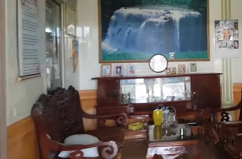 Giữa nhà là bộ bàn ghế gỗ mộc mạc. Ảnh: Youtube.