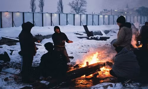 Một nhóm thanh niên tị nạn đốt lửa sưởi ấm giữa trời đêm lạnh giá ở Belgrade, Serbia. (Nguồn ảnh: Al Jazeera)