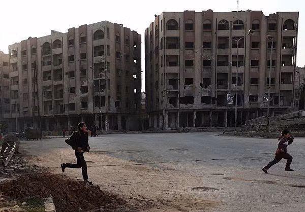 Hai em nhỏ chạy trên đường phố Aleppo sau giải phóng.