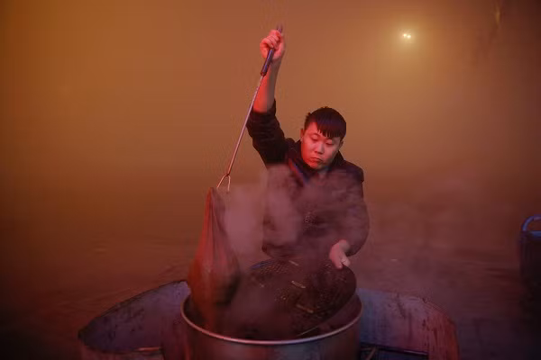 Một người đàn ông đun nấu ngoài trời ở tỉnh Hồ Bắc trong một ngày báo động đỏ về tình trạng ô nhiễm không khí ở Trung Quốc.