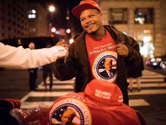 Trong ảnh, Keilaun Wilson đang bán mũ, áo phông cho những người ủng hộ ông Donald Trump hôm 20/1. Ảnh: Washington Post.