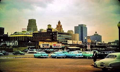 Khá nhiều ô tô đỗ trong một bãi đỗ xe. Có thể nhận thấy, đây là một thành phố phát triển của nước Mỹ.