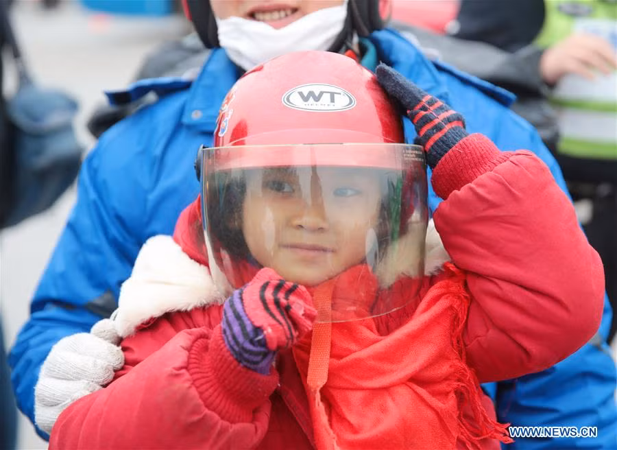 Một bé gái đội mũ bảo hiểm ngồi trên xe máy cùng bố mẹ tại trạm xăng ở Thuận Đức.