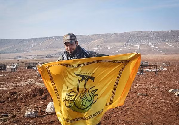 Một chiến binh của phong trào Hezbollah al-Nujaba cầm cờ của tổ chức này.