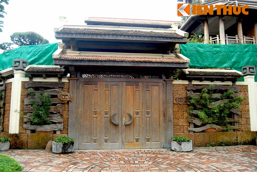 Chiếc cổng gỗ lớn, mái ngói và tay nắm cửa cách điệu sừng trâu tạo điểm nhấn lạ mắt cho biệt thự.
