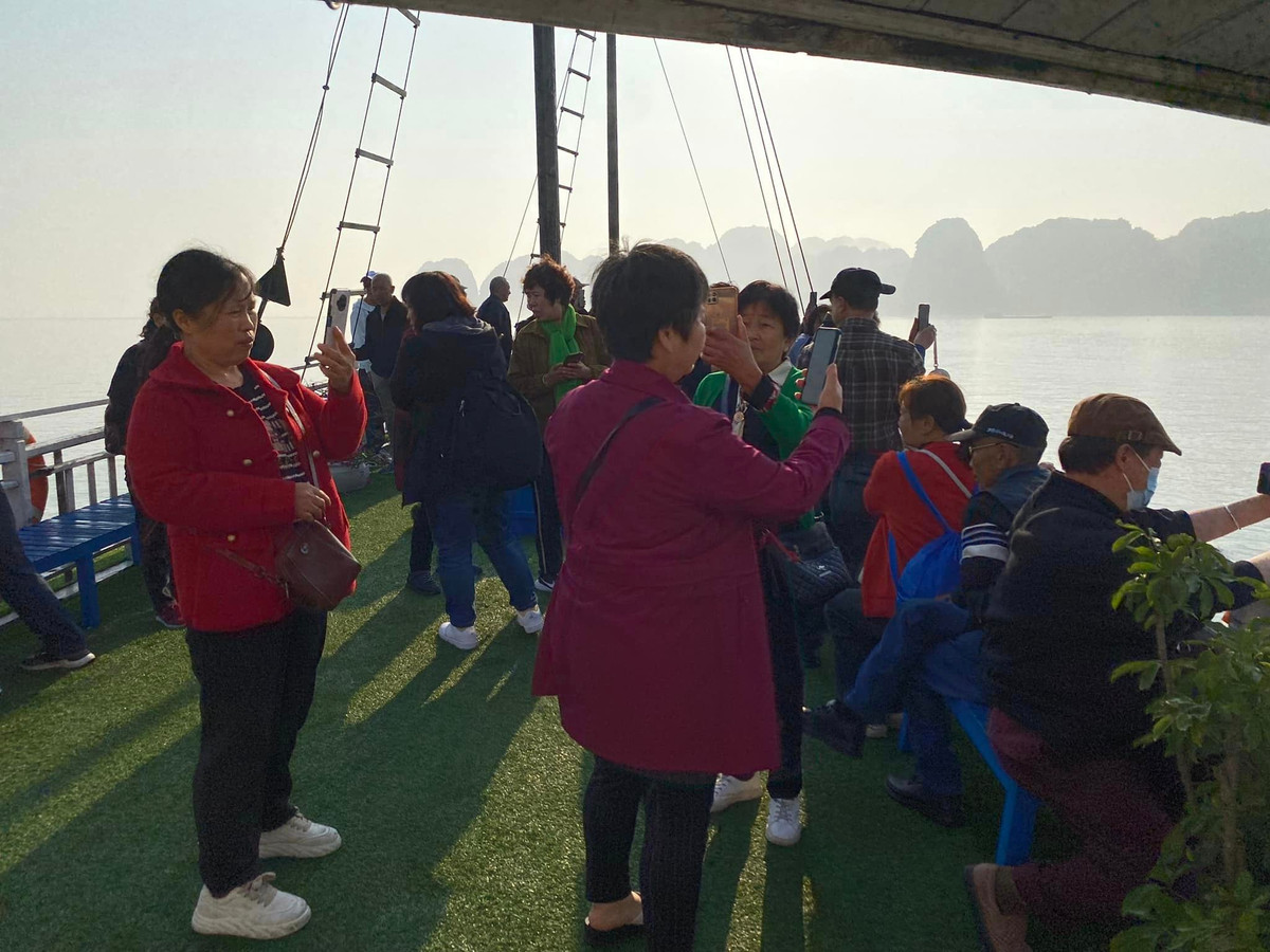 Các du khách tham quan vịnh Hạ Long mải mê chụp ảnh khi bất ngờ có sương mù phủ trắng.