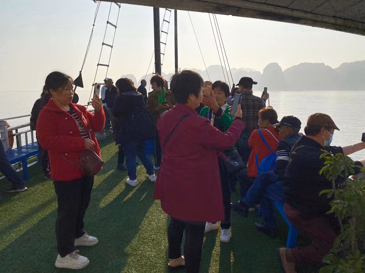 Các du khách tham quan vịnh Hạ Long mải mê chụp ảnh khi bất ngờ có sương mù phủ trắng.