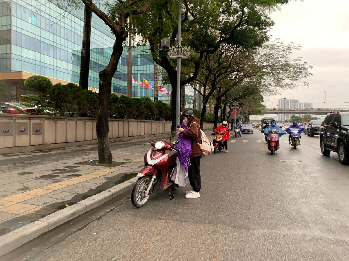 Nhiều người đi xe máy buộc phải dừng lại để mặc áo mưa.