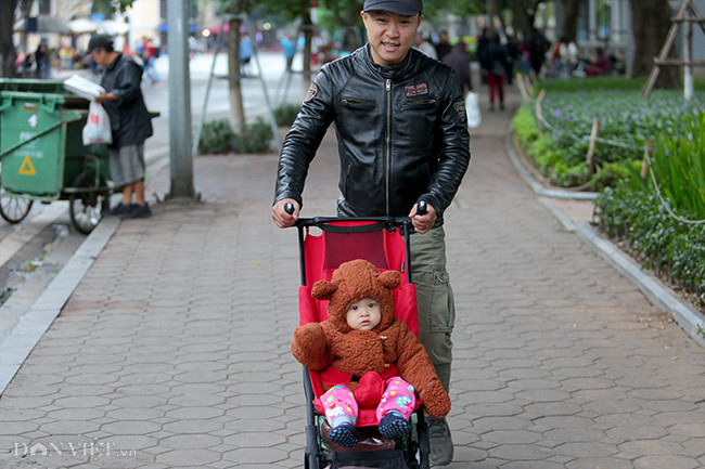 Một em nhỏ tại quận Hoàn Kiếm được bố đẩy xe đi chơi.