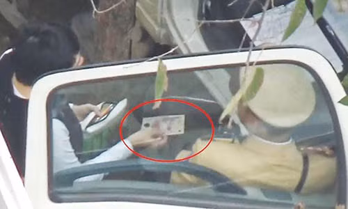 Hình ảnh người cho là vi phạm đưa một vật giống tiền cho CSGT Hà Nội để "làm luật" nhanh. Ảnh cắt từ clip.