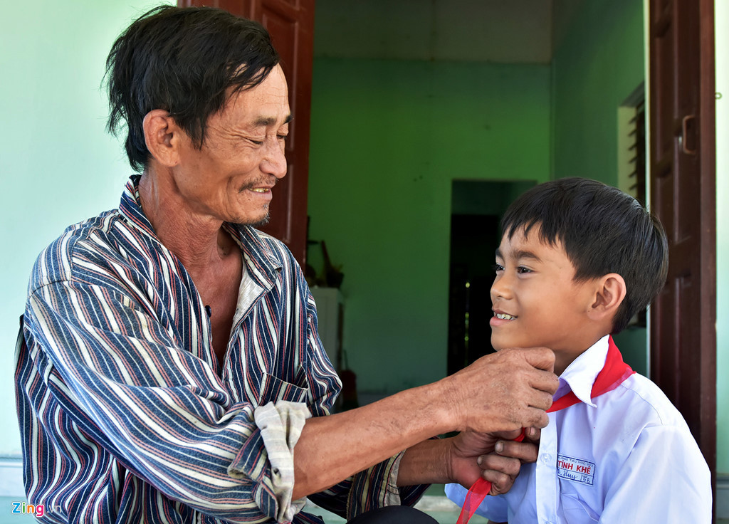 Ông Ba trò vừa đeo khăn quàng vừa trò chuyện vui vẻ cùng con trai trước giờ đến trường. Ảnh: Minh Hoàng.