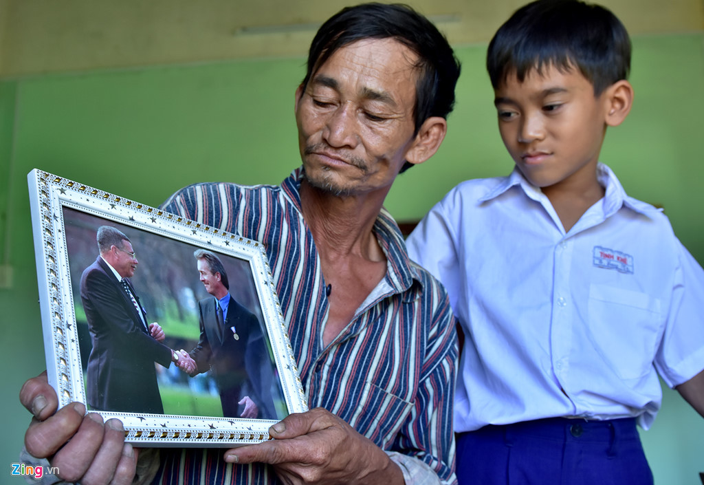 Ông Đỗ Ba bên bức ảnh phi công Mỹ Hugh Thompson và Lawrence Colburn, hai ân nhân cứu sống mình trong vụ thảm sát Mỹ Lai. Ảnh: Minh Hoàng.