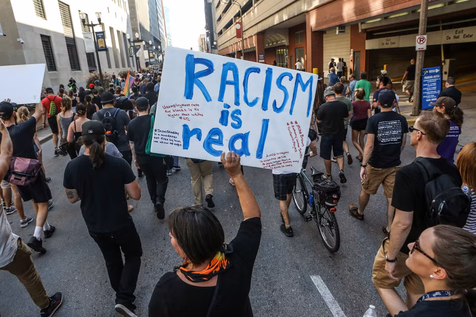 Cuộc biểu tình phản đối vụ người da đen bị bắn chết thu hút sự tham gia của cả người da đen và da trắng. Vụ việc giữa cảnh sát Stockley và nghi phạm Smith, bị tình nghi bán ma túy, xảy ra năm 2011. Khi bị cảnh sát truy đuổi, Smith lái ôtô chạy trốn buộc cảnh sát phải đuổi theo. Sau màn truy bắt trên phố, xe của nghi phạm đâm vào lề buộc anh phải dừng lại. Lúc này, Stockley cho biết Smith cũng mang theo súng nên anh phải nổ súng trước vì lo sợ nguy hiểm cho bản thân.