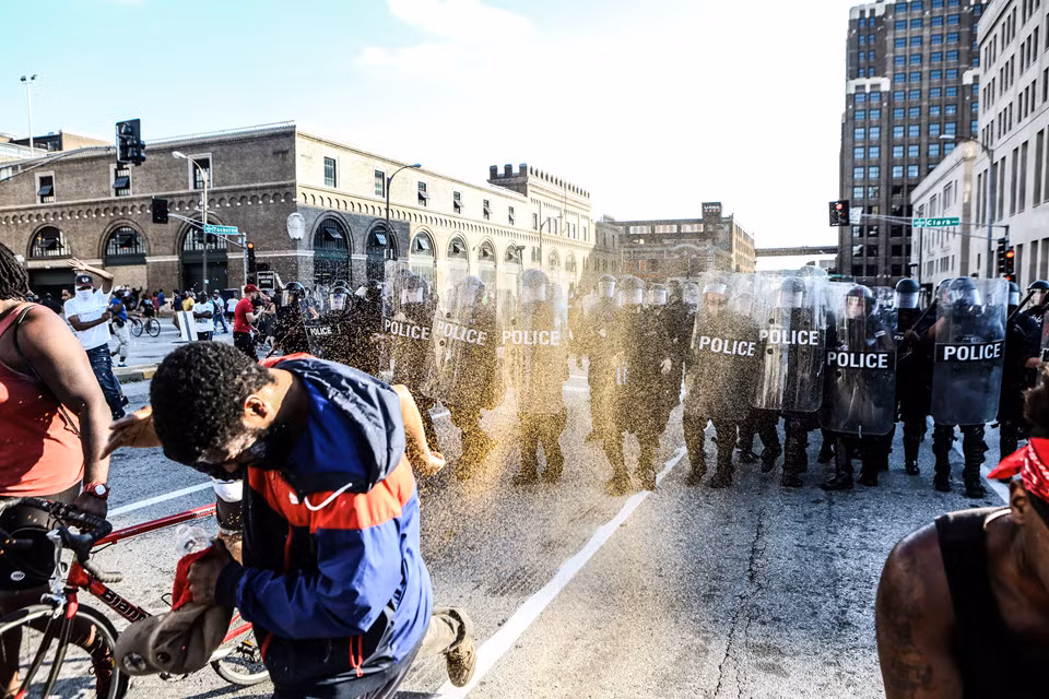 Một người che mặt để tránh hơi cay phun từ phía cảnh sát.