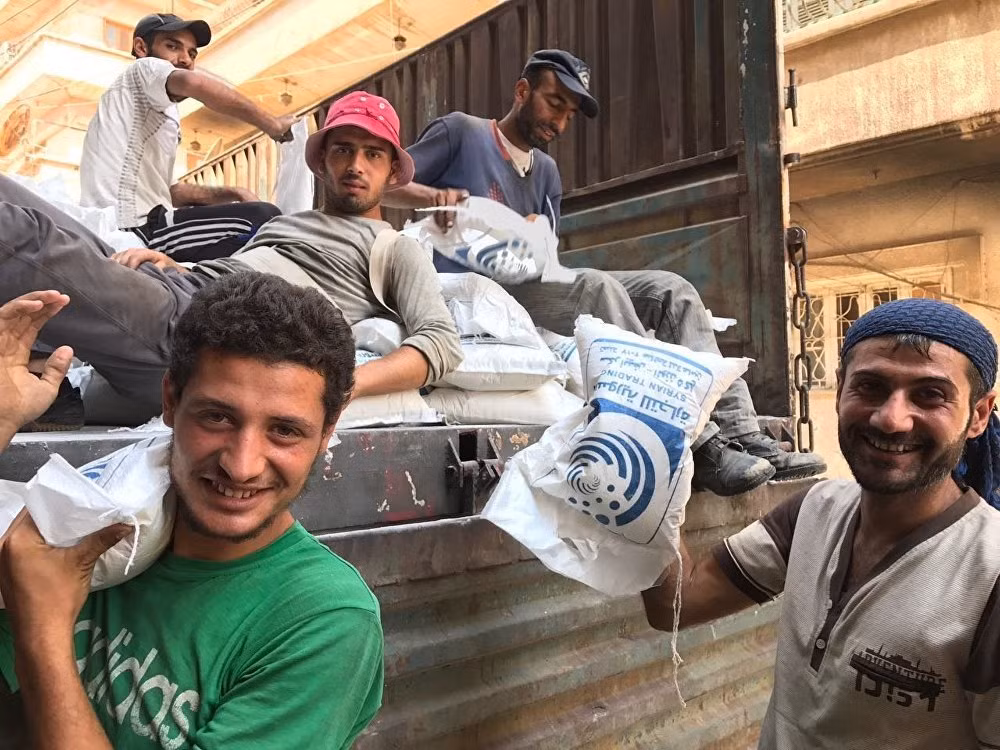 Người dân Syria đang bắt đầu tái thiết thành phố Deir Ezzor sau khi thoát khỏi vòng vây suốt 3 năm của nhóm khủng bố IS. Ảnh: Những người đàn ông lấy bao đường từ xe tải xuống ở Deir Ezzor. Ảnh: Sputnik.