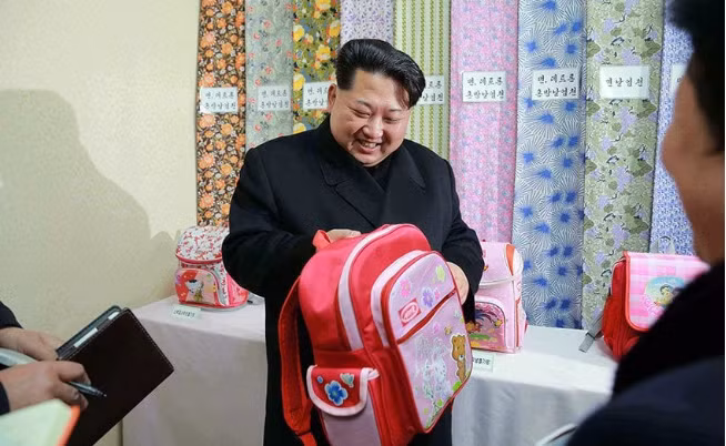 Nhà lãnh đạo Triều Tiên Kim Jong-un cầm một chiếc ba lô học sinh khi tới thăm nhà máy dệt Kim Jong-suk ở thủ đô Bình Nhưỡng. Ảnh: Telegraph.