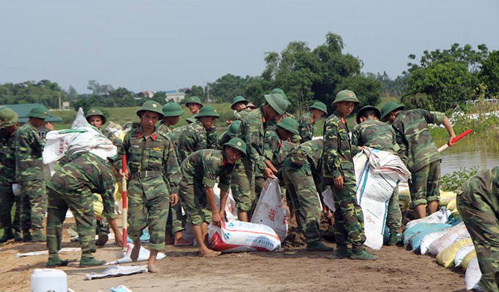 Bộ đội và người dân đang tích cực chèn bao cát, ngăn nước lũ tràn qua đê.